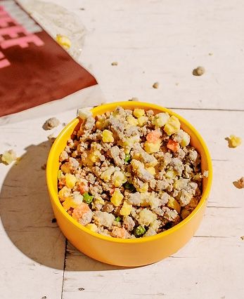 A yellow bowl of Nom Nom dog food